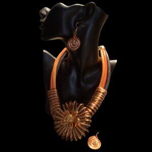 Ornate brass and gold necklace with amber colored stones in the center of the fl